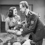  
Negatív fotografie z filmu Mladé srdcia (1952). Pri váze s kvetmi sa skláňajú Hana  Kavalírová (Naďa) a v uniforme Karol Machata (Leštiak)