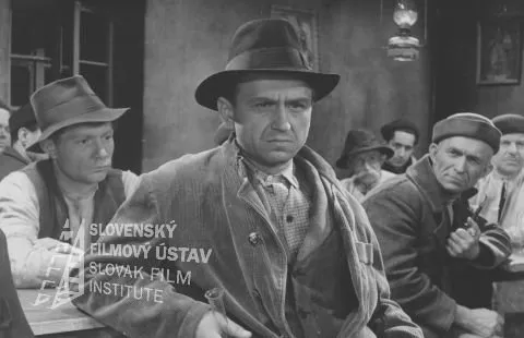 Gustáv Valach (Marek Cudrák) zdroj: skcinema.sk 
Fotografia z filmu Pole neorané (1953). V krčme v strede sedí Gustáv Valach (Marek Cudrák)