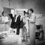  
Negatív fotografie z filmu V piatok, trinásteho... (1953). V kuchyni stoja zľava doprava: Eva Krížiková (Oľga Rebrová), Ondrej Jariabek (Jozef Rebro), Oľga Adamčíková (Rebrová) a František Dibarbora (Fero Rebro)