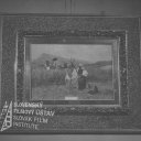  
Obraz s ľudovým motívom, v hrubom ráme je malý obraz a na ňom žena s kolískou na poli